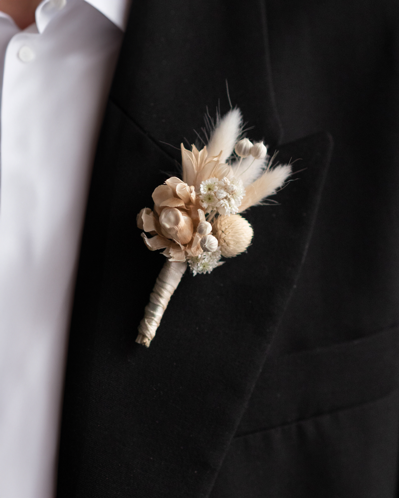 Small dried flower boutonniere finished with ribbon on a jacket