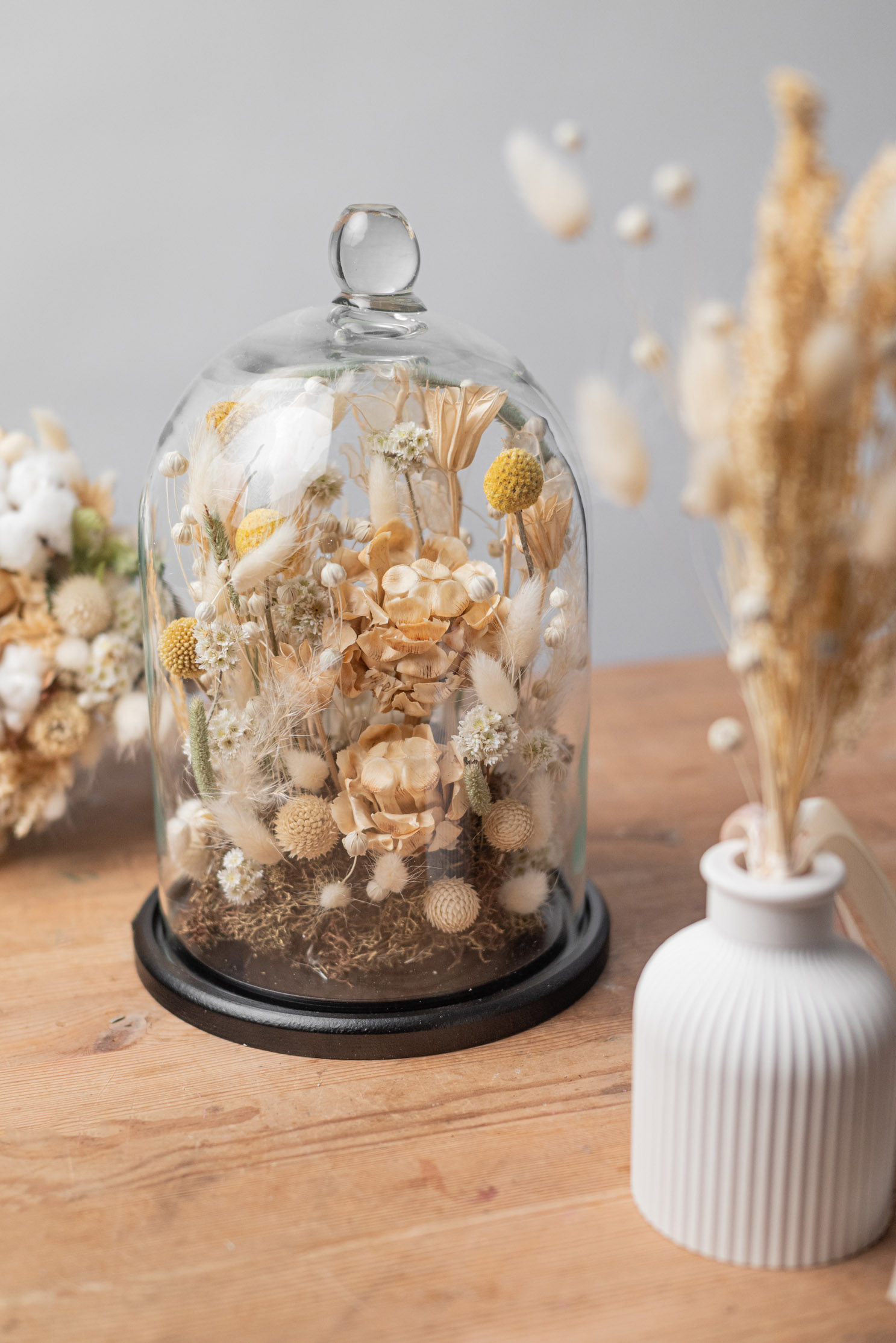 Dried flower composition displayed under a glass cloche